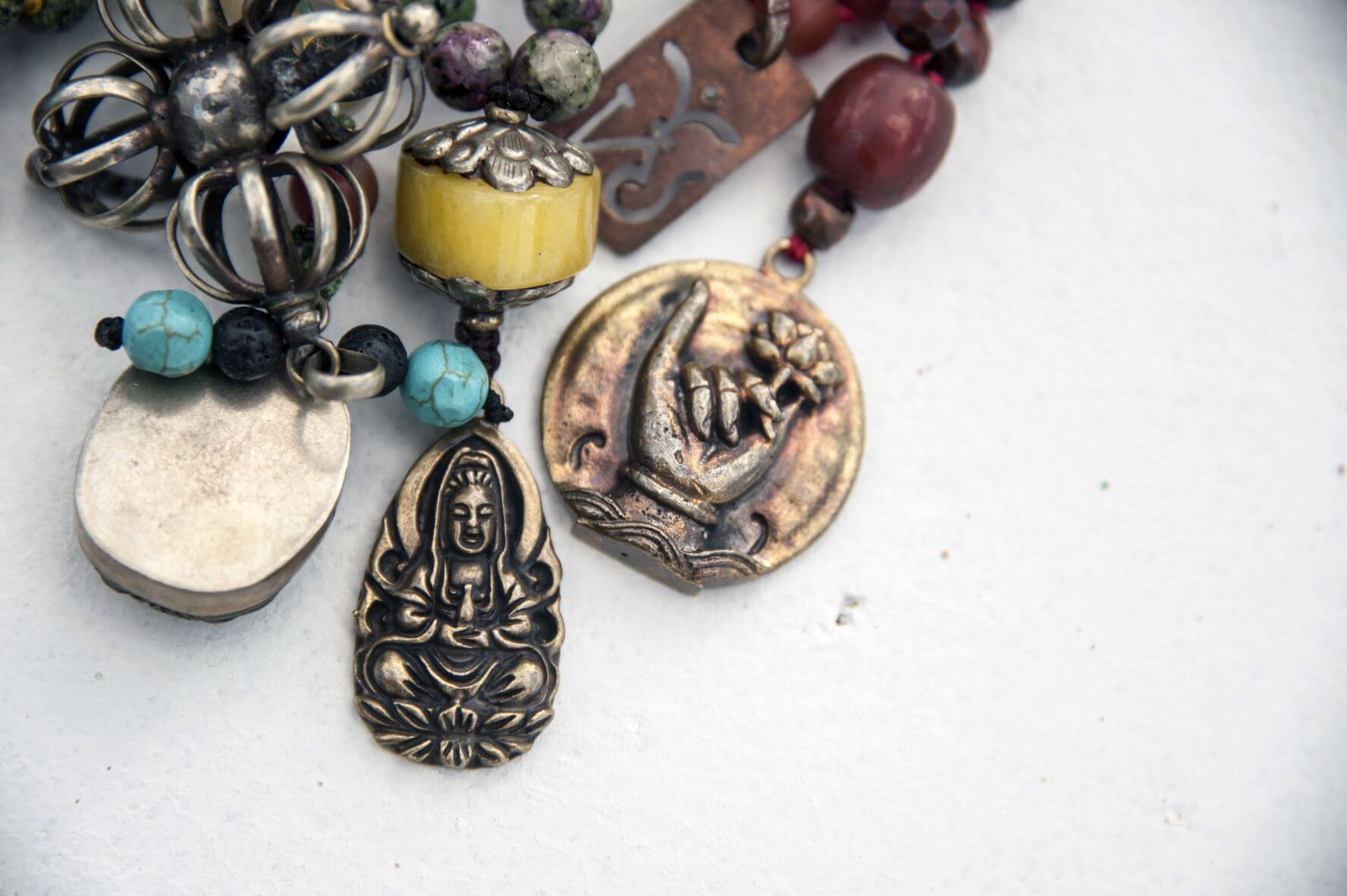 Sacred mala pendants of a buddha and a hand in mudras with a lotus