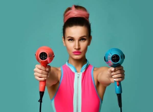 Woman holding two bright coloured hair dryer