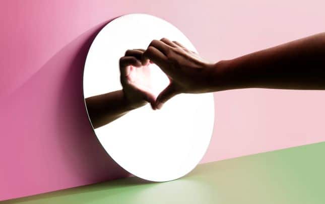 Person make heart shape with their hand against a mirror