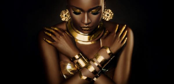 An African lady adorned in gold jewellery including earring, bangles and necklaces